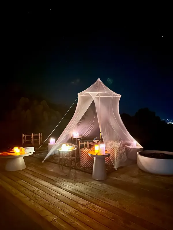 A white canopy lit by lanterns on a wooden deck at night