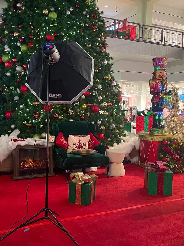 A holiday photo set with a Christmas tree, velvet armchair, wrapped gifts and studio lighting
