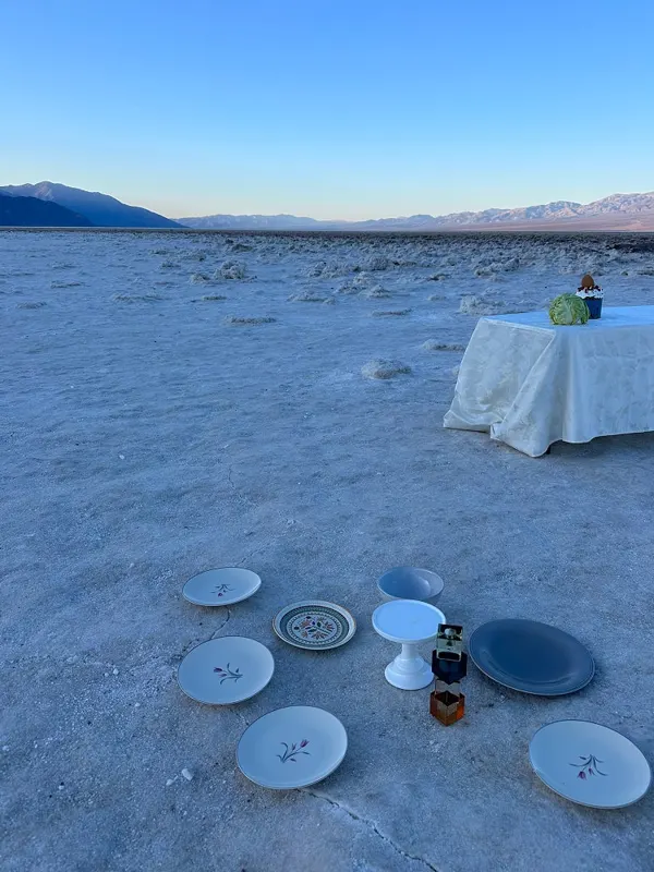A draped table and scattered plates on a salt flat at golden hour