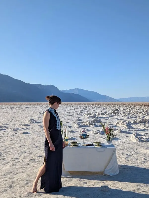 Setting a dinner table on a white salt flat in the desert, mountains beyond