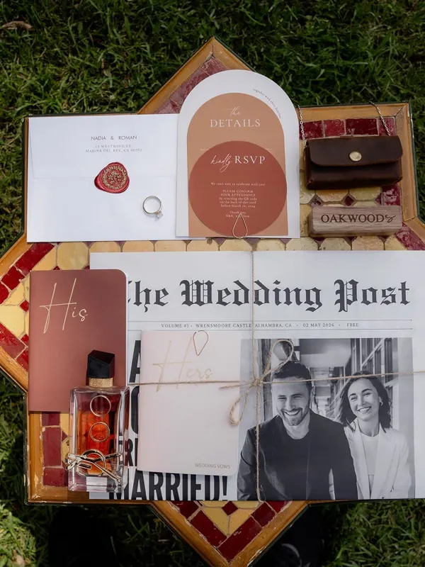 Wedding stationery flat lay with a newspaper-style invitation, RSVP card and wax-sealed envelope
