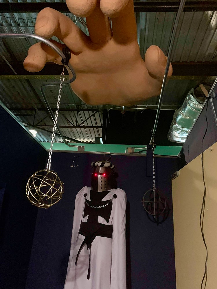 A theatrical installation with a giant sculpted hand and a knight figure with glowing red eyes